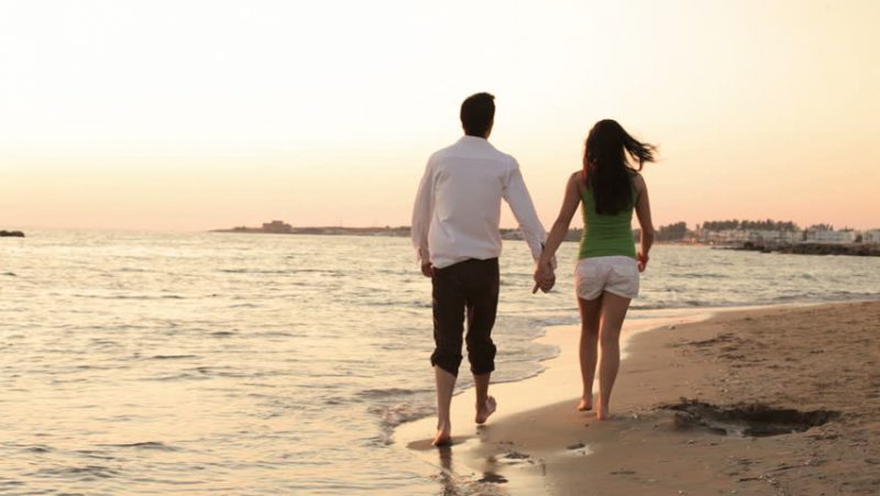a couple holding hands and walking down the beach