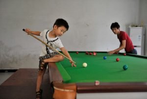 Three-year-old Wang Wuka practises snooker as his father positions the balls on the table at their home in Xuancheng