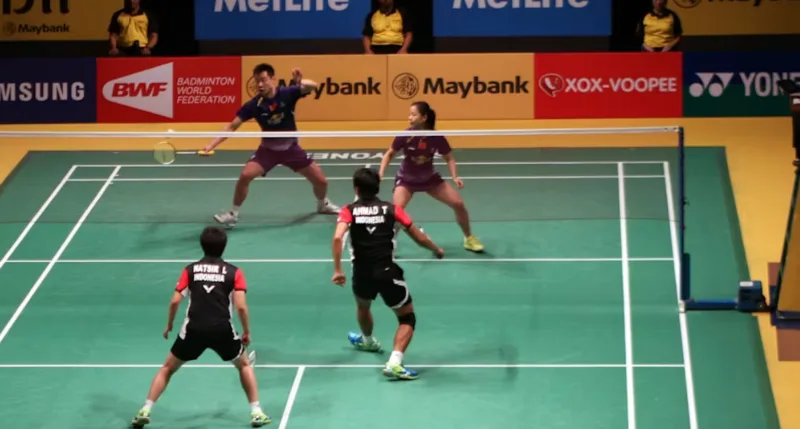 four people playing badminton doubles