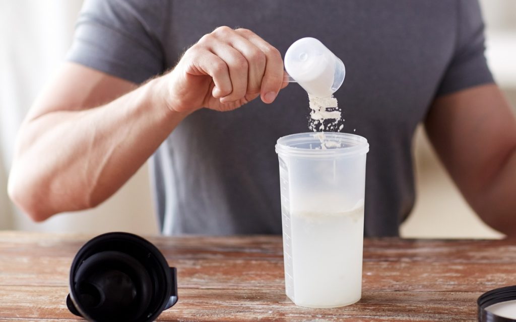 man pouring protein powder in a bottle